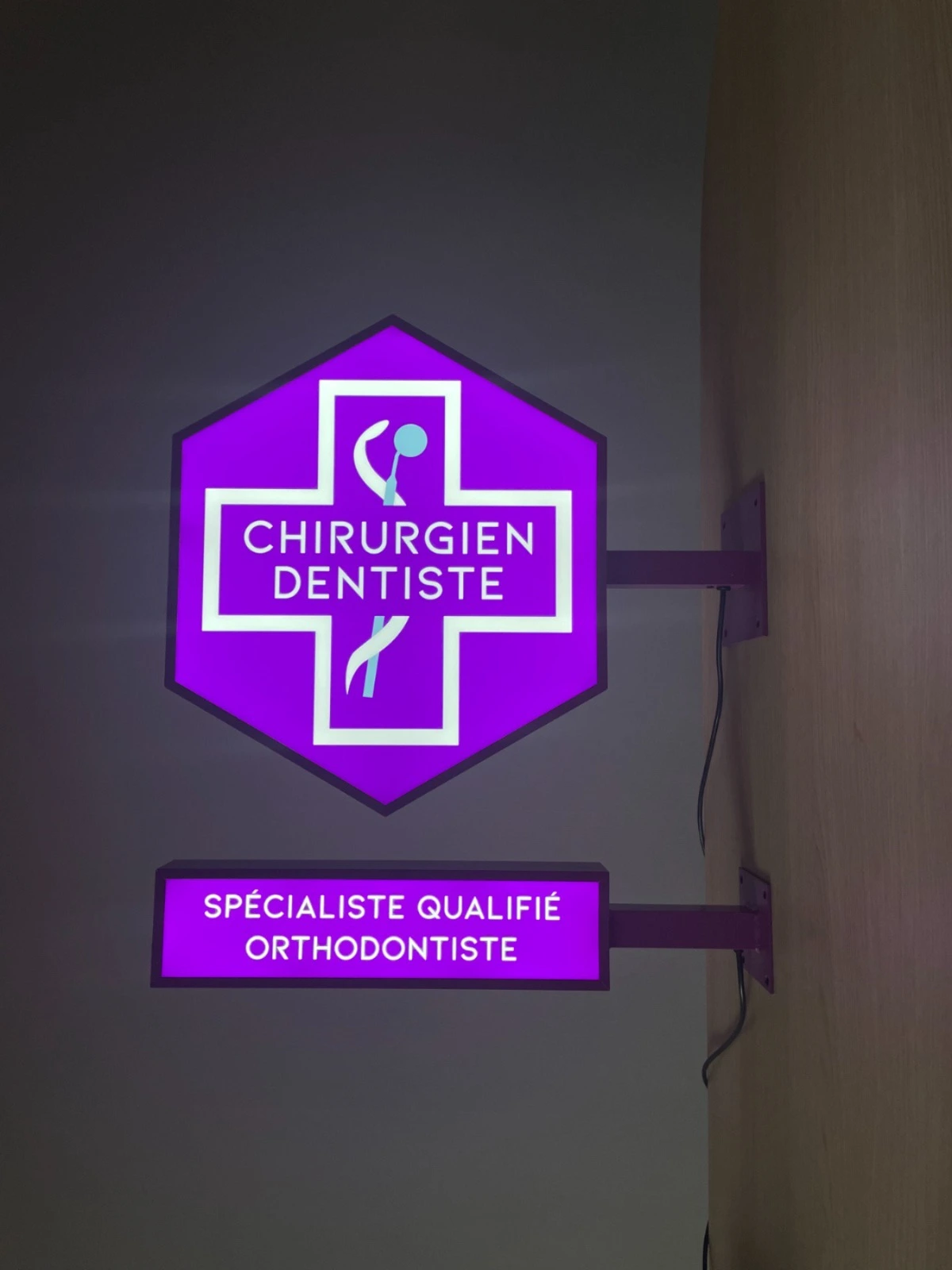 enseigne drapeau lumineuse et module de spécialité orthodontiste installés sur un mur
